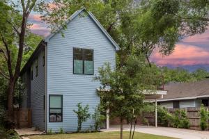 een blauw huis met bomen ervoor bij Pristine Pool Palace 6BR - Rainey St - 7min walk in Austin