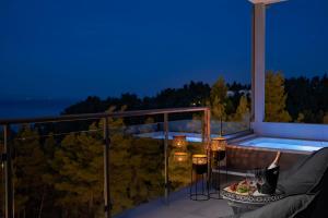 a woman sitting on a balcony with a table with a drink at Mirabilia Boutique Hotel in Kriopigi