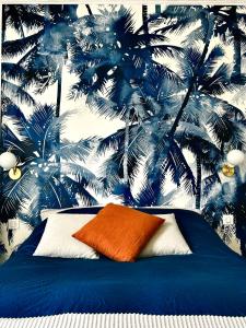 Bett mit orangefarbenem Kissen vor einer Palmenwand in der Unterkunft Appartement charmant et lumineux ! in Boulogne-Billancourt