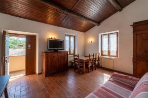 ein Wohnzimmer mit einem TV und einem Tisch mit Stühlen in der Unterkunft Residenza Cerreto-Casalini in Panicale