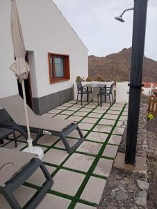 a patio with chairs and an umbrella on a house at Calma Suites Tejeda in Tejeda