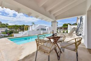 un patio con mesa, sillas y piscina en Villas Guzman - San Vicente en Moraira