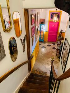 a stairway with a pink door and pictures on the wall at Aux couleurs de Commarin in Commarin