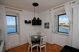 ein Esszimmer mit einem Tisch und 2 Fenstern in der Unterkunft PORT in Makarska