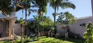 a backyard with a table and chairs and palm trees at Family Comfort, Casa residencial Aconchegante in Foz do Iguaçu