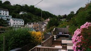 a wooden deck with chairs and flowers in a town at Commanders Cabin EV point in Looe