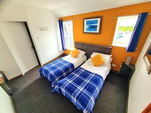 two beds in a room with orange walls and windows at Elemental Surf Lodge in Newquay