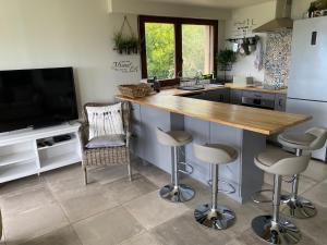 a kitchen with a counter with stools and a television at Dieu L'Amour - Molinard in Châteauneuf