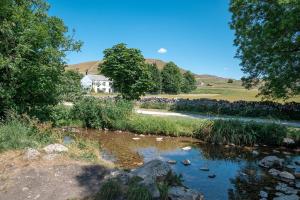 a river with a house in the background with a house at Miresfield Farm Bed & Breakfast in Malham