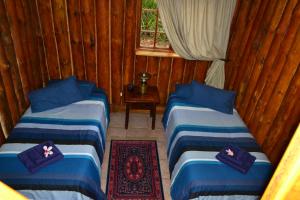 three beds in a room with wooden walls at On Golden Pond - Mount Amanzi in Hartbeespoort