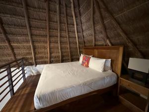ein Schlafzimmer mit einem Bett in einem strohgedeckten Zimmer in der Unterkunft Na Balam Hotel in Isla Mujeres
