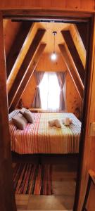 een bed in een houten kamer met een raam bij Paluna cabaña in San Martín de los Andes