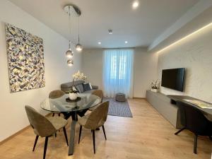 ein Wohnzimmer mit einem Tisch, Stühlen und einem TV in der Unterkunft Clavis Luxury Apartments in Chiavenna