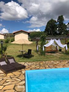 einen Pool mit Sonnenschirm, Tisch und Stühlen in der Unterkunft Chalés para temporada - Chalés Apuã - 500 metros da Cachoeira in Carrancas