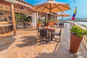 a patio with tables and chairs and an umbrella at GHL Collection Armería Real Hotel in Cartagena de Indias