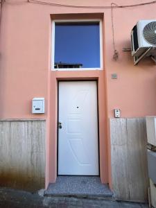 a pink building with a white door and a window at LA CASETTA in Cagliari