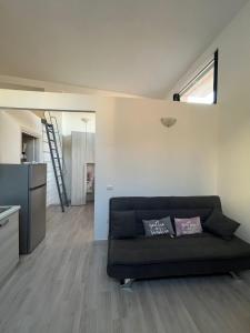 a living room with a black couch and a kitchen at LA CASETTA in Cagliari