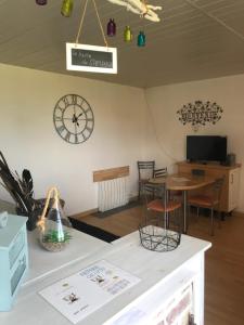 Zimmer mit einem Tisch und einer Uhr an der Wand in der Unterkunft Chambre d'hôtes "COQUELICOT" in Nurlu