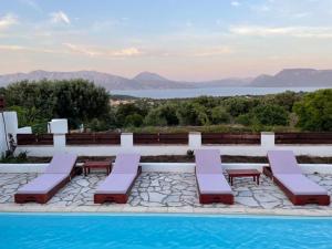 a pool with lounge chairs and a view of the water at Hestia's House in Meganisi