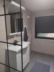 ein Bad mit einem weißen Waschbecken und einem Fenster in der Unterkunft Kosmajska Vila in Koraćica