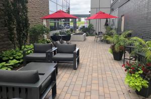 un patio con sillas, mesas y sombrillas rojas en Courtyard by Marriott Burlington-Oakville en Burlington