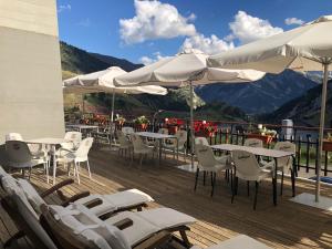 una terraza con mesas, sillas y sombrillas blancas en Hotel Edelweiss Candanchú, en Candanchú