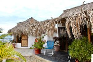 a house with a thatched roof and a blue chair at Marina Bungalows in Los Órganos