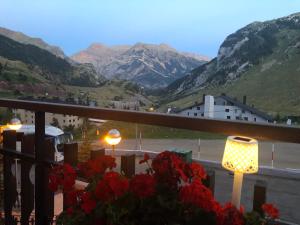 a view of mountains from a balcony with red flowers at Hotel Edelweiss Candanchú in Candanchú