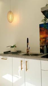 een keuken met witte kasten en een hanglamp bij Hotel Jugend with Self Check-in in Liepāja