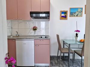 een keuken met roze kasten en een tafel bij Apartments Neda in Omiš
