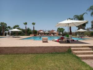 uma piscina com guarda-sóis e cadeiras e uma piscina em Marrakech M Avenue CR 7 appart terrasse em Marraquexe