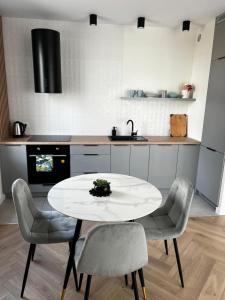 una cocina con mesa blanca y sillas. en Apartament Szmaragdowy., en Siedlce