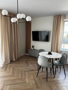 uma sala de jantar com uma mesa e cadeiras e uma televisão em Apartament Szmaragdowy. em Siedlce