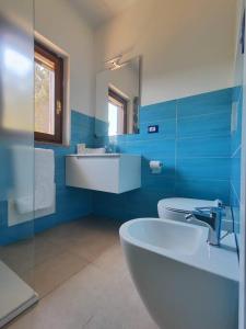 ein blaues Bad mit einem Waschbecken und einem WC in der Unterkunft Alma Ruia apartments in Stintino