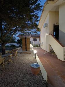 ein Haus mit einer Terrasse mit Stühlen und einem Baum in der Unterkunft Alma Ruia apartments in Stintino