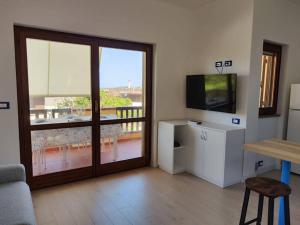 ein Wohnzimmer mit einer Glasschiebetür und einem TV in der Unterkunft Alma Ruia apartments in Stintino