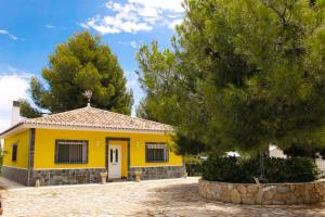 a yellow house with a tree in front of it at Casa rural en Casas de Moya 'Casa del Pino Gori' 