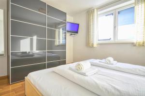 Schlafzimmer mit einem weißen Bett und einem TV in der Unterkunft Apartment Leon - by Alpen Apartments in Zell am See