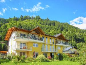 ein großes gelbes Gebäude mit einem Berg im Hintergrund in der Unterkunft Apartment Leon - by Alpen Apartments in Zell am See