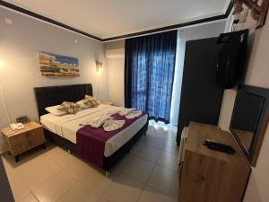 Schlafzimmer mit einem Bett, einem TV und einem Fenster in der Unterkunft Hotel Lunay in Antalya