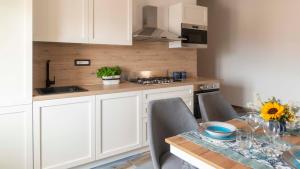 una cucina con armadi bianchi e un tavolo con tavolo. di Welcomely - Loft Gabbiani Cala Gonone a Cala Gonone