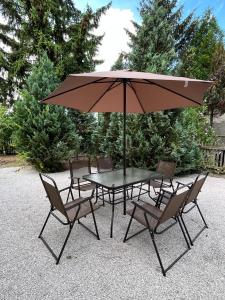 a table and chairs with a large umbrella at Dom ALEX pri kúpalisku Thermalpark in Dunajská Streda