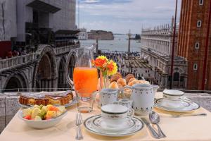 Canaletto Luxury Suites - San Marco Luxury في البندقية: طاولة مع طعام ومشروبات على طاولة مطلة