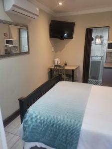 a bedroom with a bed and a tv on the wall at Giardino a 194 in Welkom