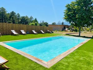 a swimming pool in the middle of a lawn with chairs at Résidence de la Plage in Porto-Vecchio