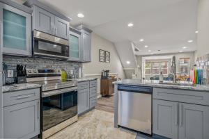 a large kitchen with stainless steel appliances and gray cabinets at Uptown Gem! 2Luxe King Suites - Deck - Parking in Philadelphia