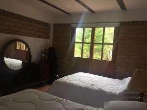 a bedroom with two beds and a mirror and a window at Refugio Villa Emilio in Villa de Leyva