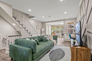 uma sala de estar com um sofá verde e uma escada em Uptown Gem! 2Luxe King Suites - 5 Smart TV's - Parking em Filadélfia
