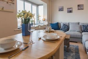 a wooden table with plates and wine glasses on it at Links Bay - 100 yards from beach and golf course in Deal