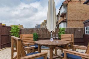 a wooden table with two chairs and an umbrella at Links Bay - 100 yards from beach and golf course in Deal
